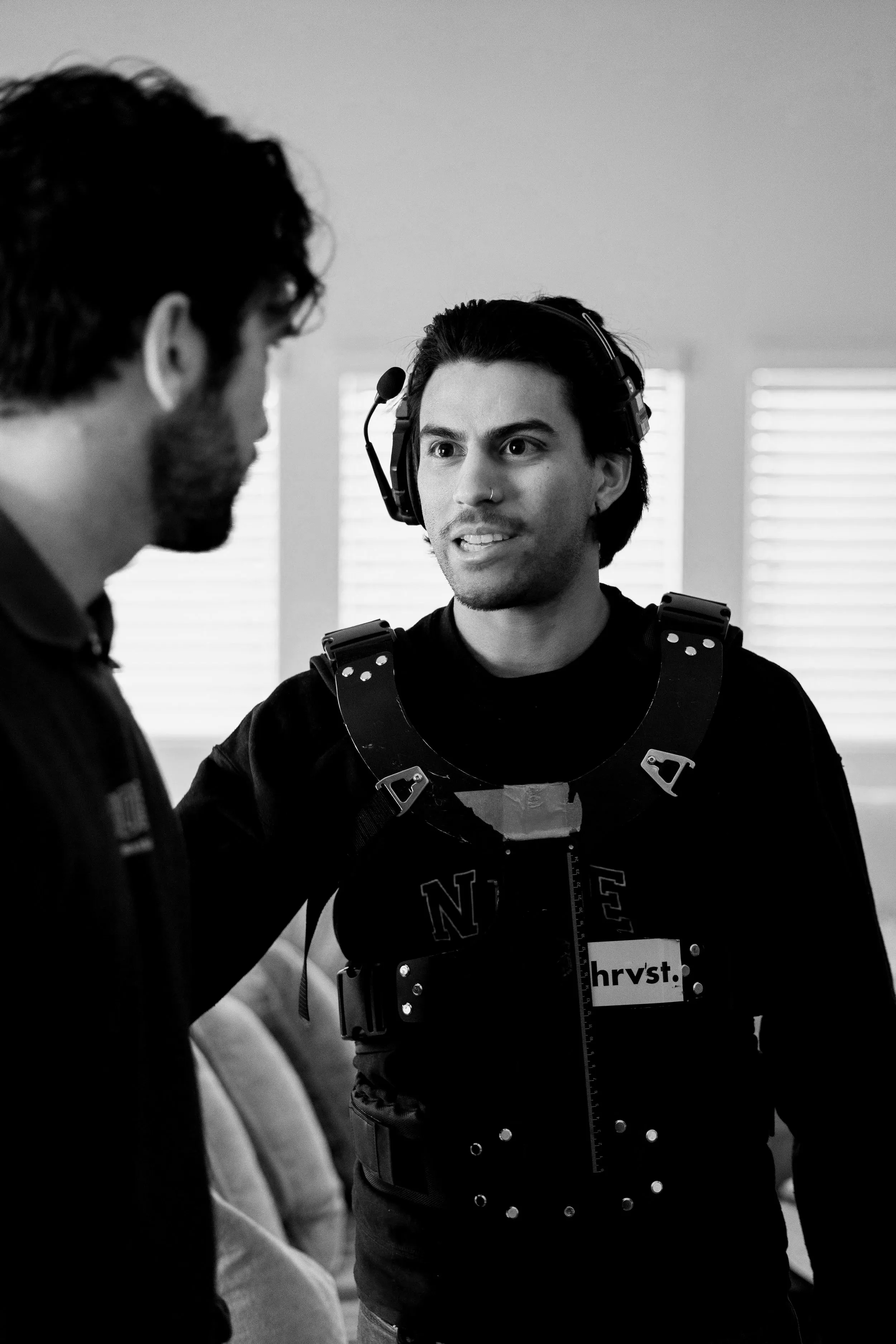 Black and white photo of a performer in a motion-capture suit talking with a crew member.