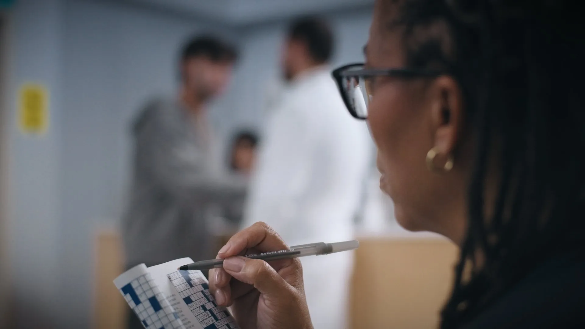 Over-the-shoulder shot of a woman filling in a crossword puzzle.