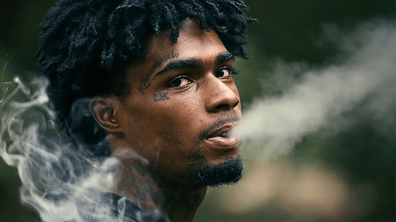 Young man exhaling smoke in a dramatic close-up portrait.