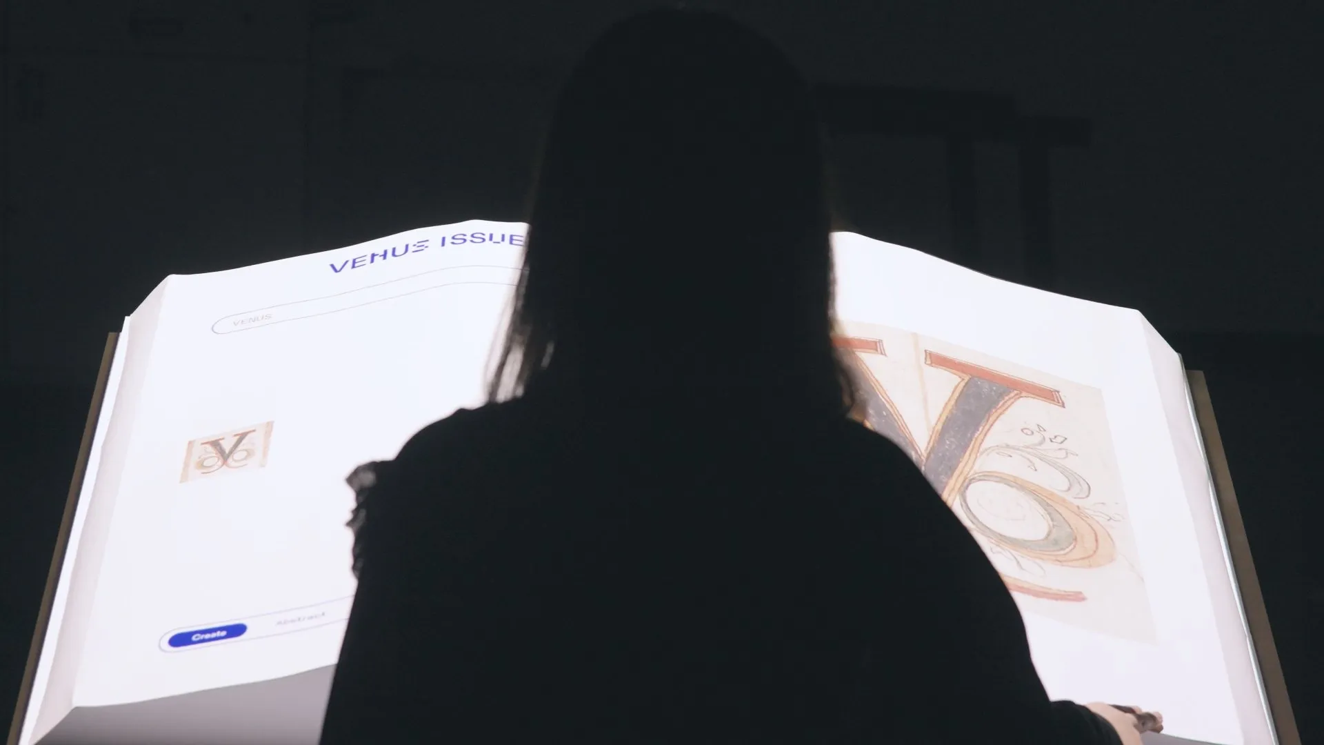Woman viewing a glowing interactive typography display of the letter V.
