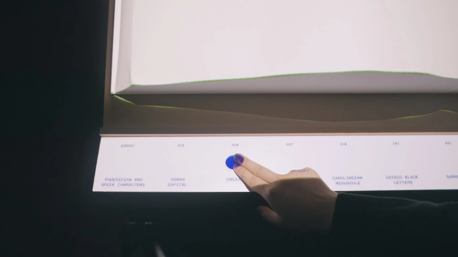 Finger selecting an option on a backlit interactive typography display.