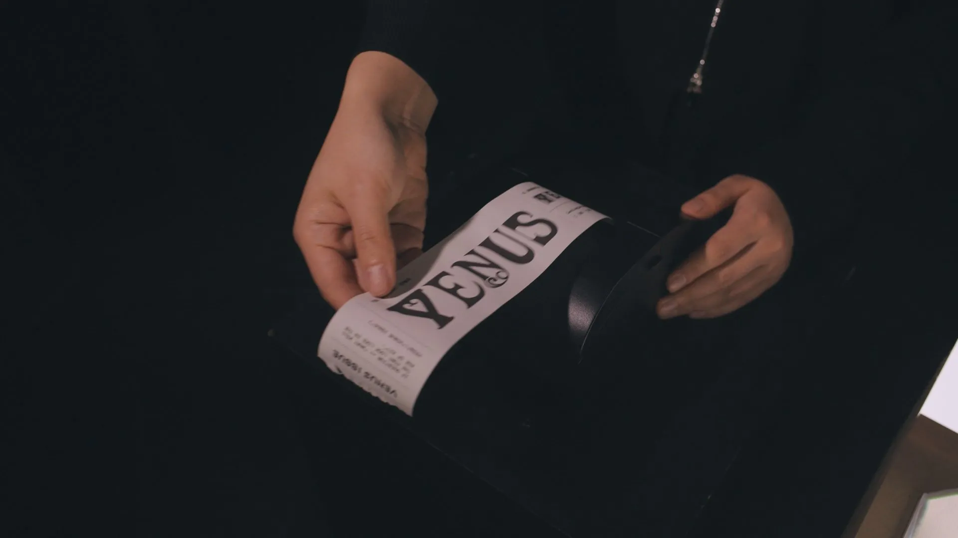 Hands holding a printed Venus Issue ticket.